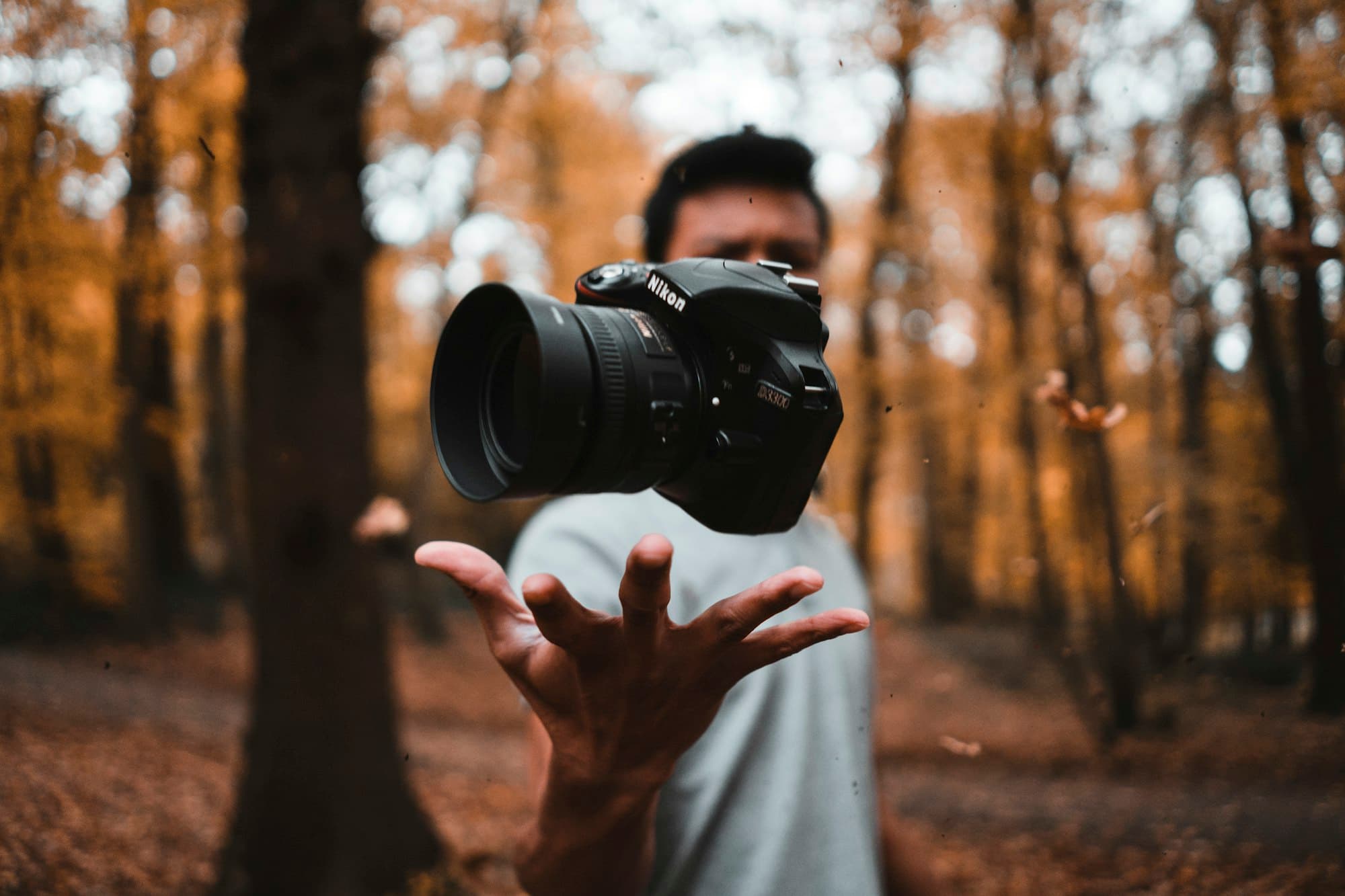 Person hält eine Kamera in einem herbstlichen Wald in die Kamera